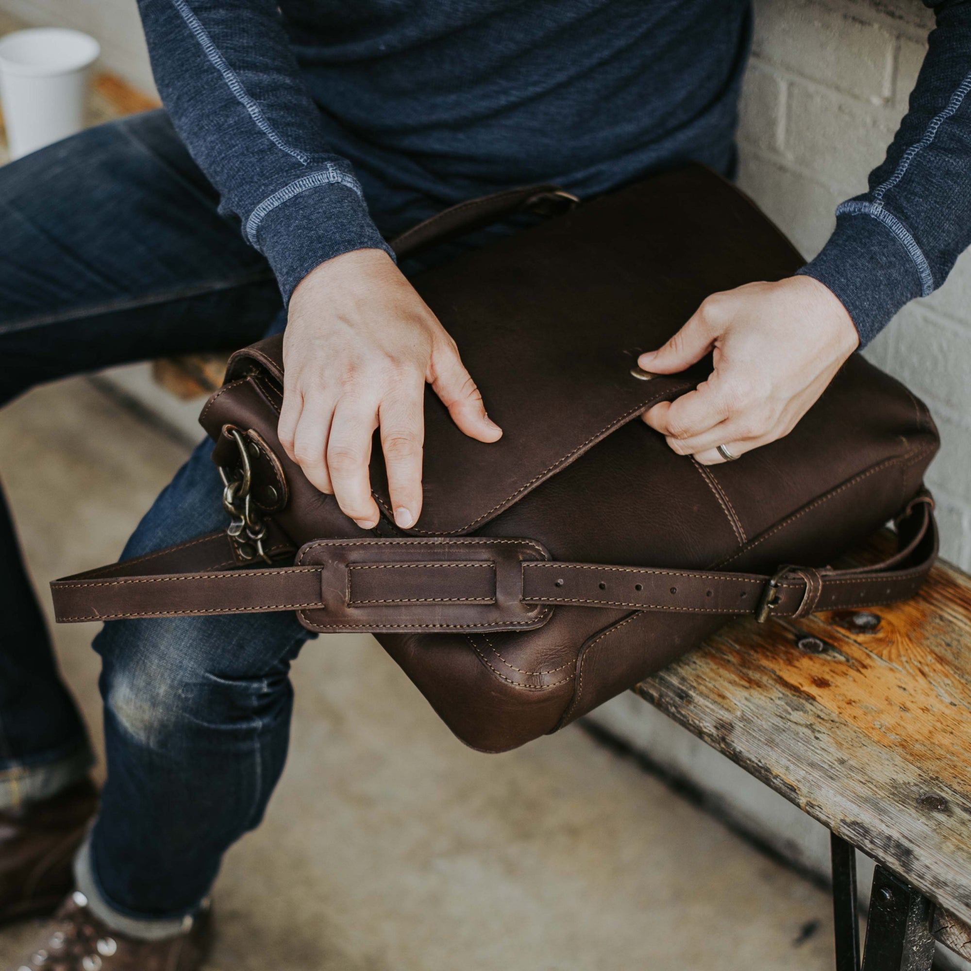 Man at outdoor table with Roosevelt Leather Messenger Bag — Dark Oak full-grain leather, adjustable strap detail